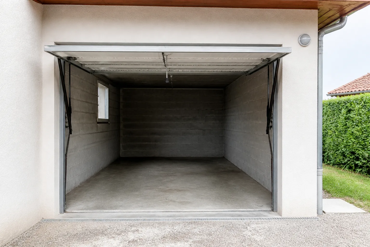 Garage de maison au niveau du terrain avec seuil et porte basculante