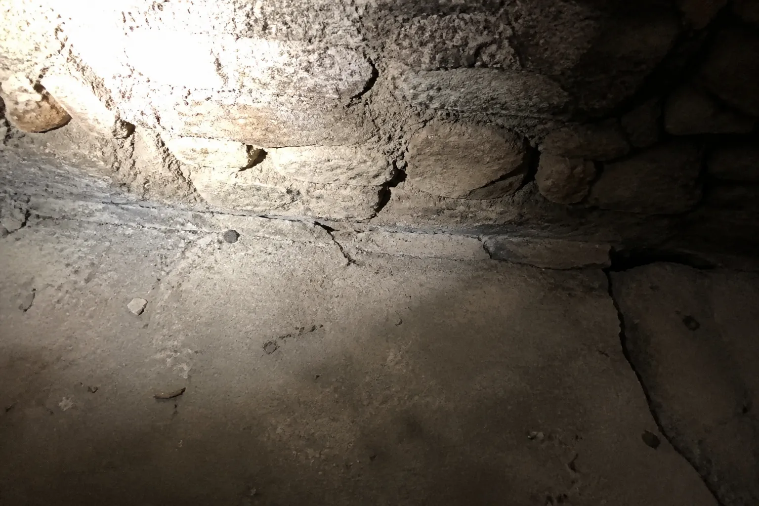 Sol de cave affaissé et fissure au pied d’un mur ancien
