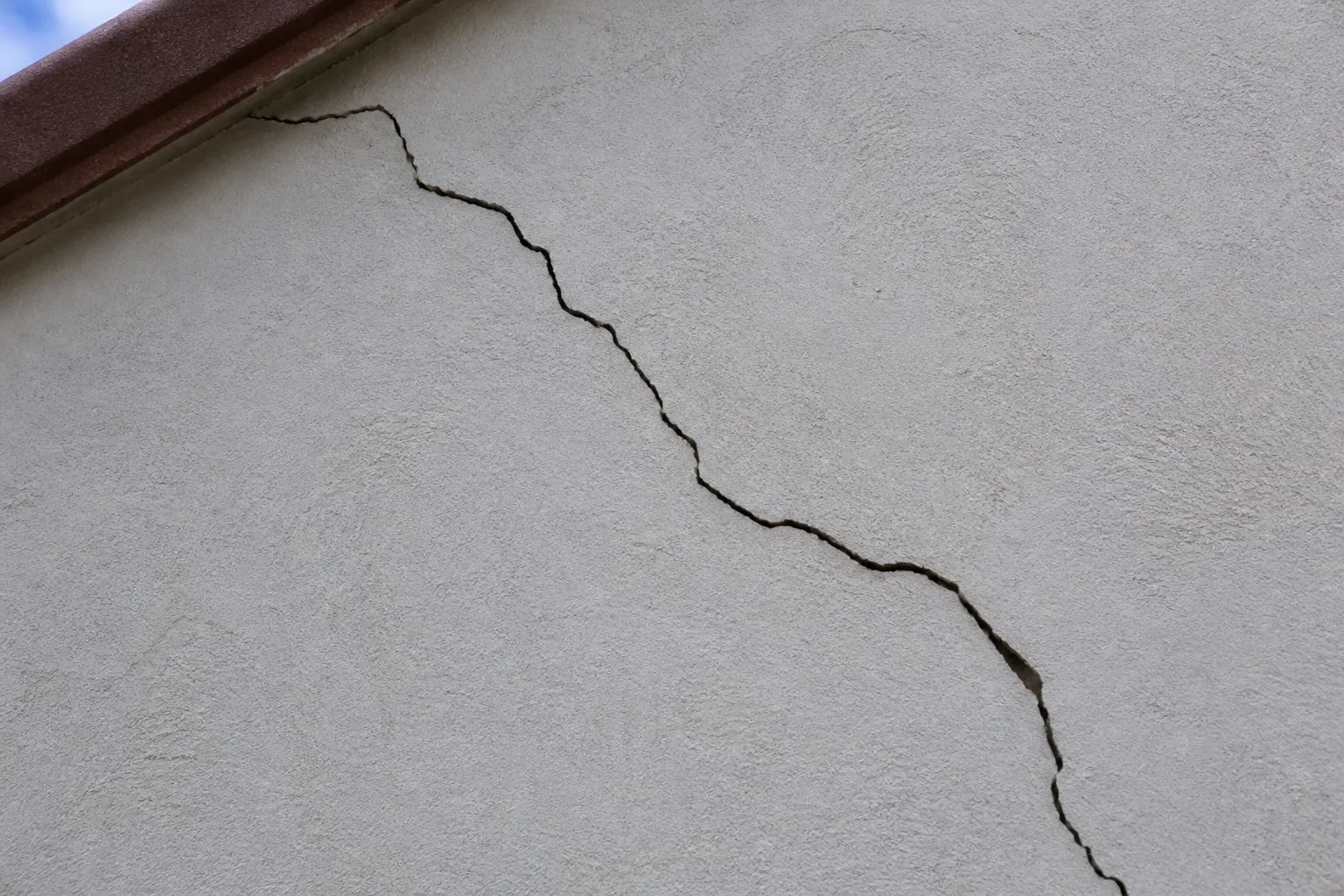 Fissure sur un mur de façade enduit d’un pavillon