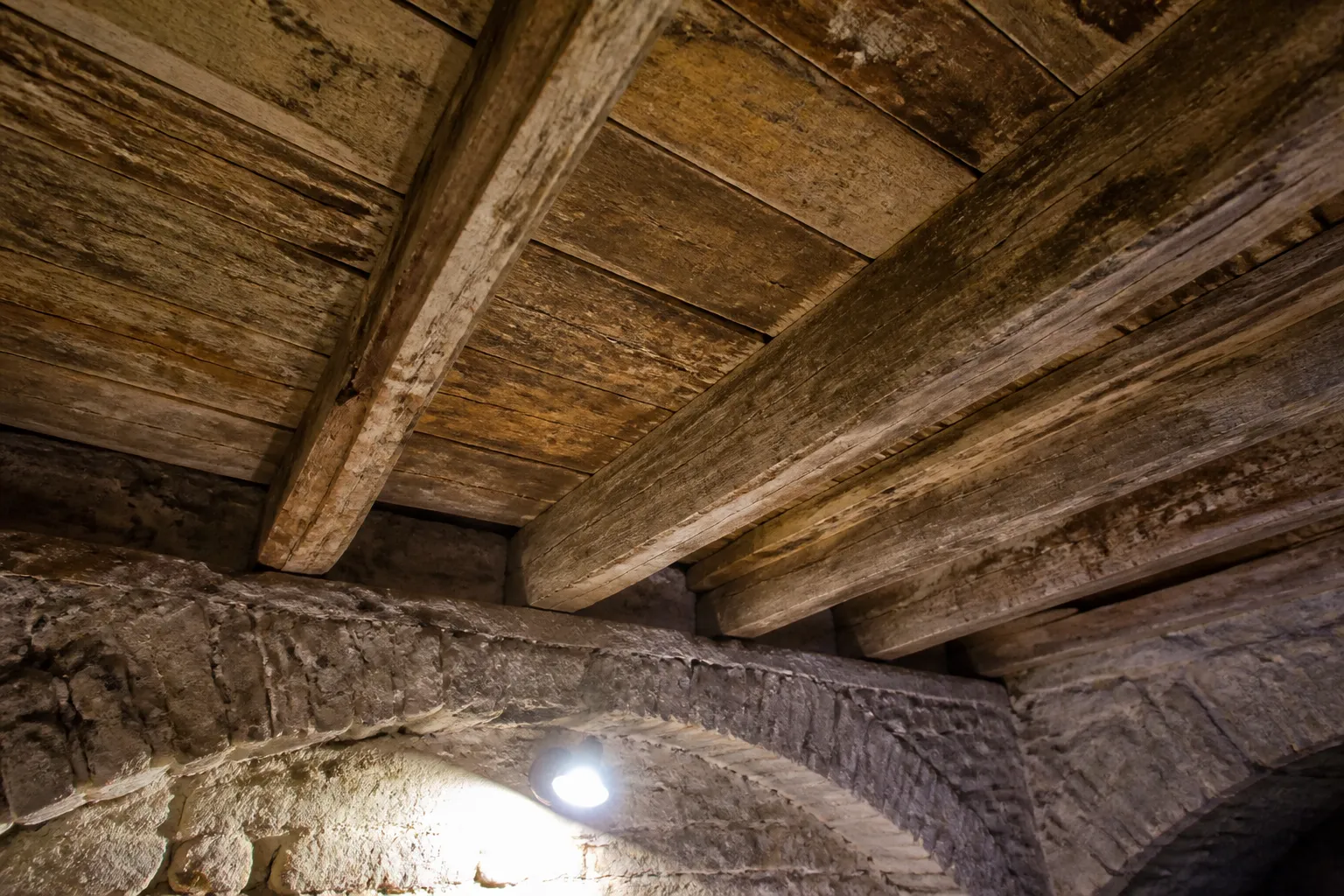 Plancher et solives en bois observés depuis une cave
