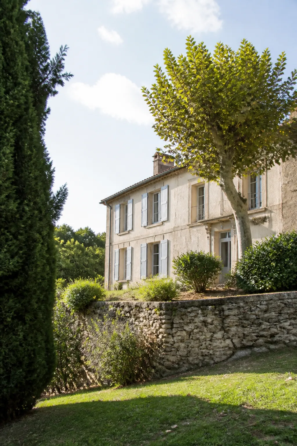 Maison ancienne sur un terrain en pente avec mur de soutènement
