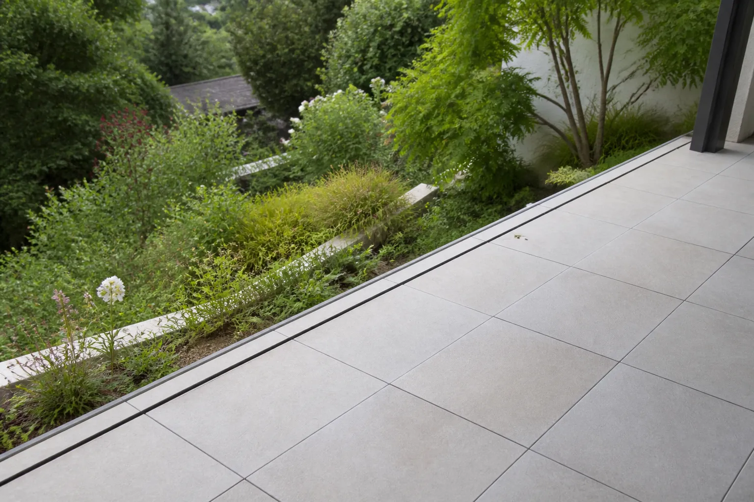 Terrasse carrelée avec joint de dilatation au bord d’un jardin