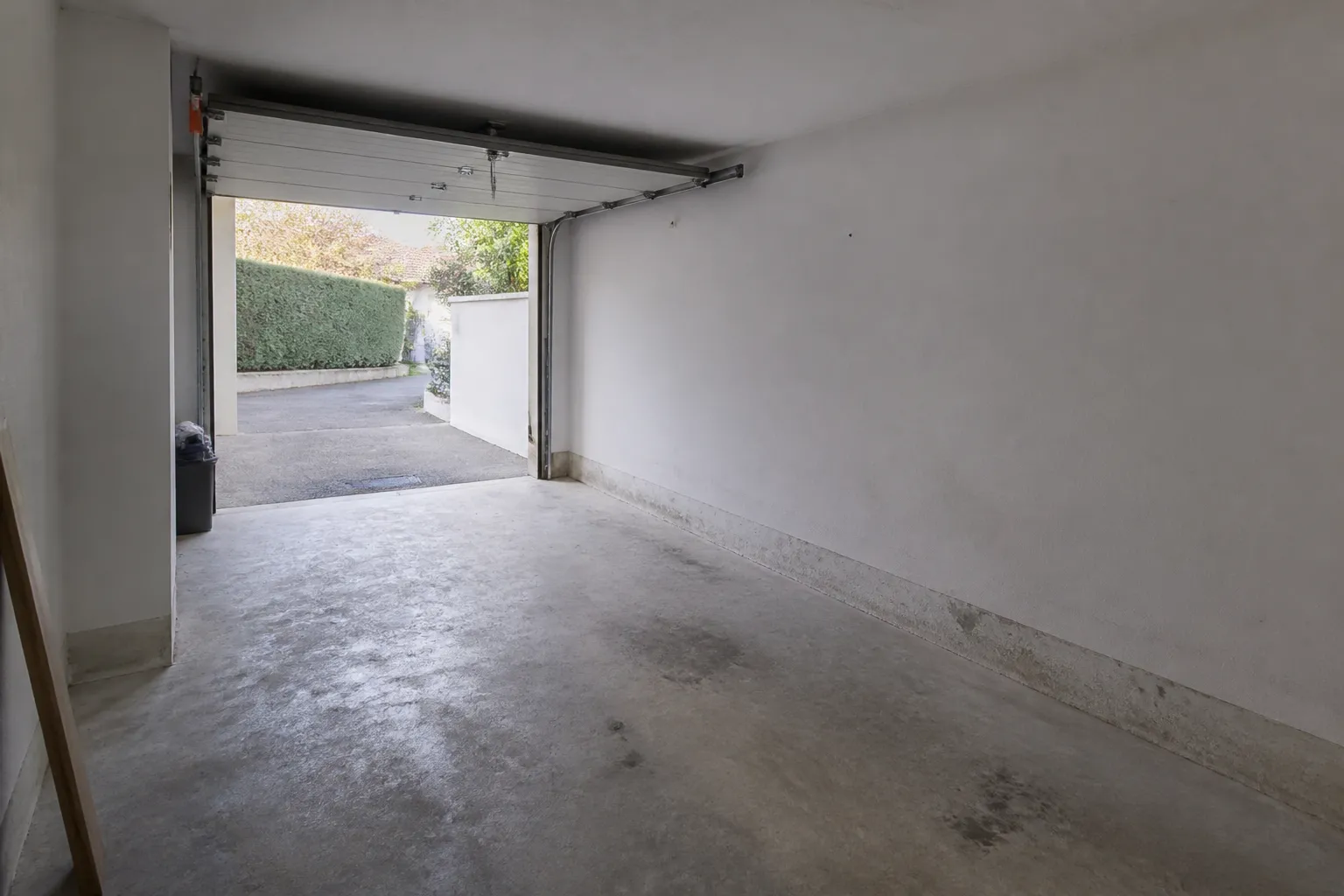 Garage en rez-de-chaussée avec sol béton et traces au bas des murs