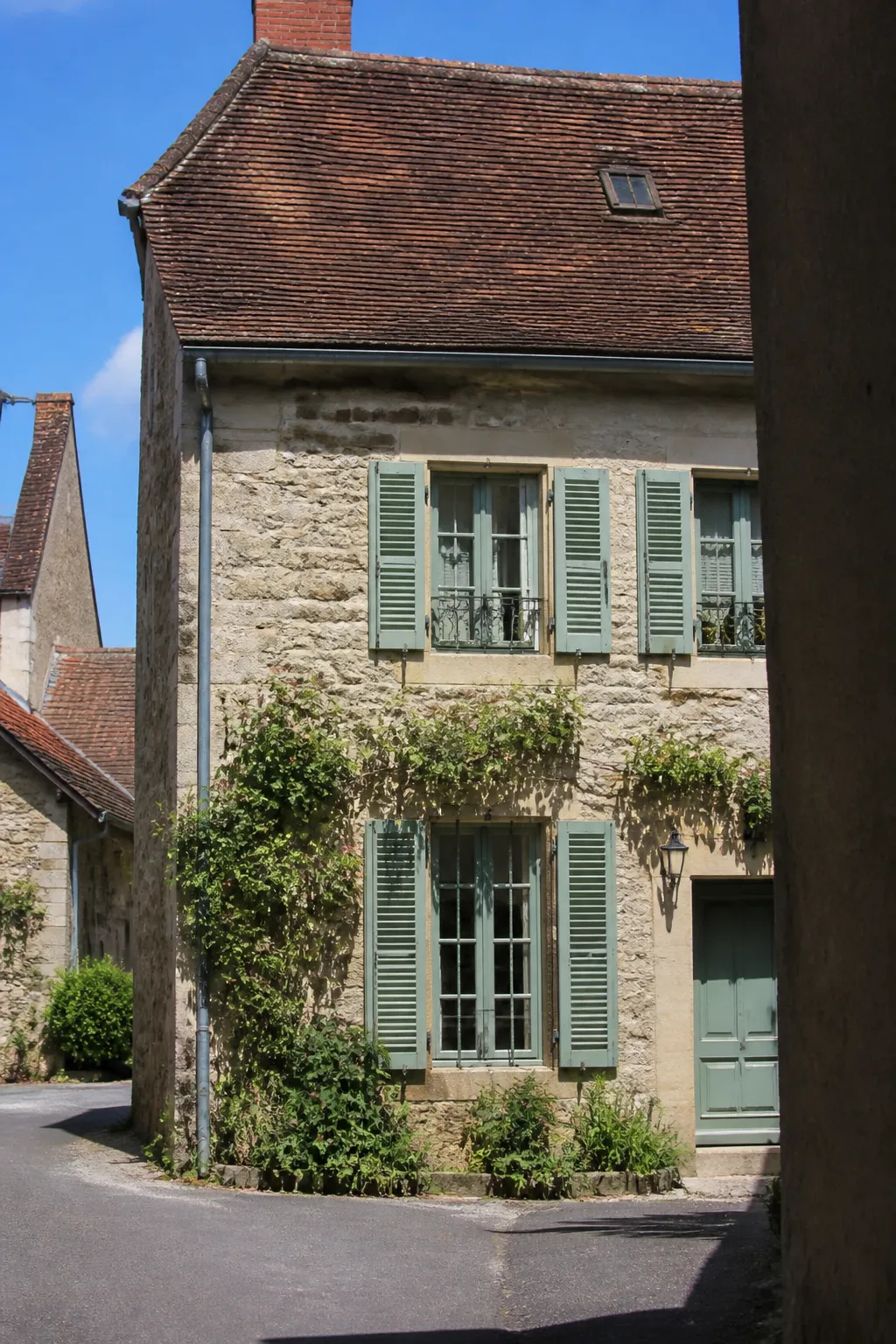 Maison ancienne en pierre avec toit de tuiles et volets peints
