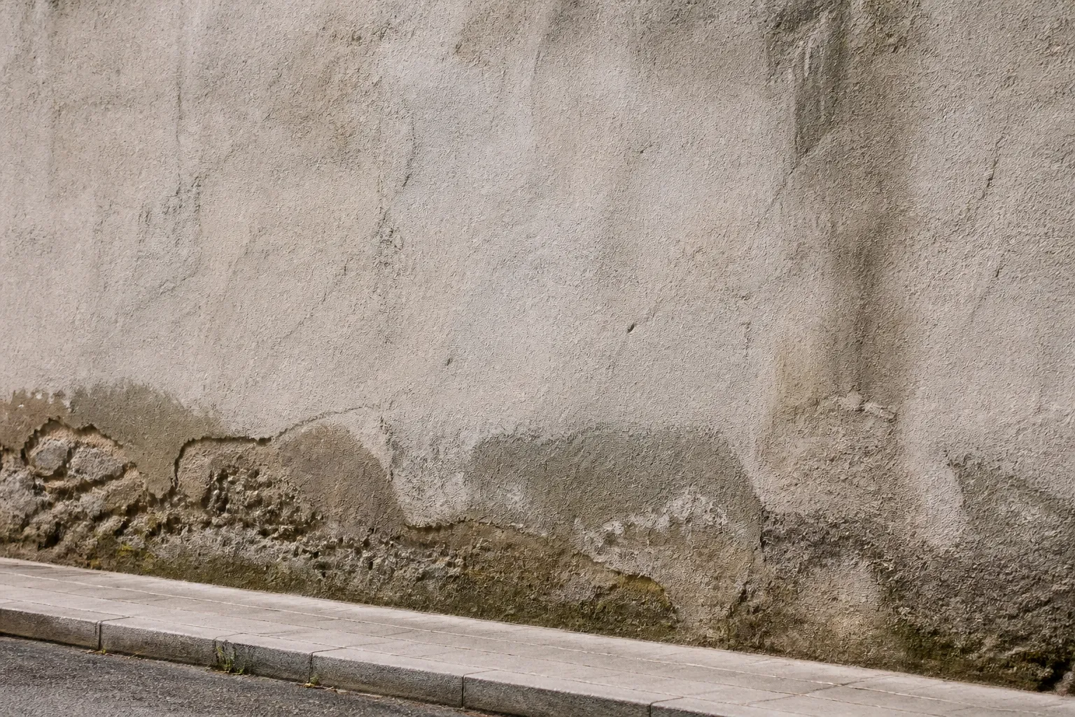 Mur mitoyen ancien avec enduit dégradé au pied
