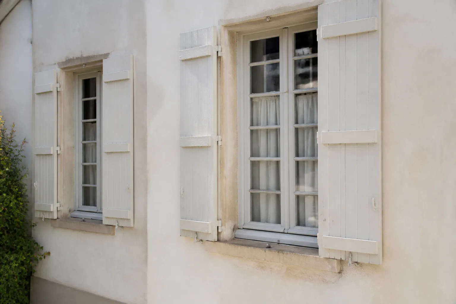 Fenêtres anciennes en bois à petits carreaux sur une façade enduite