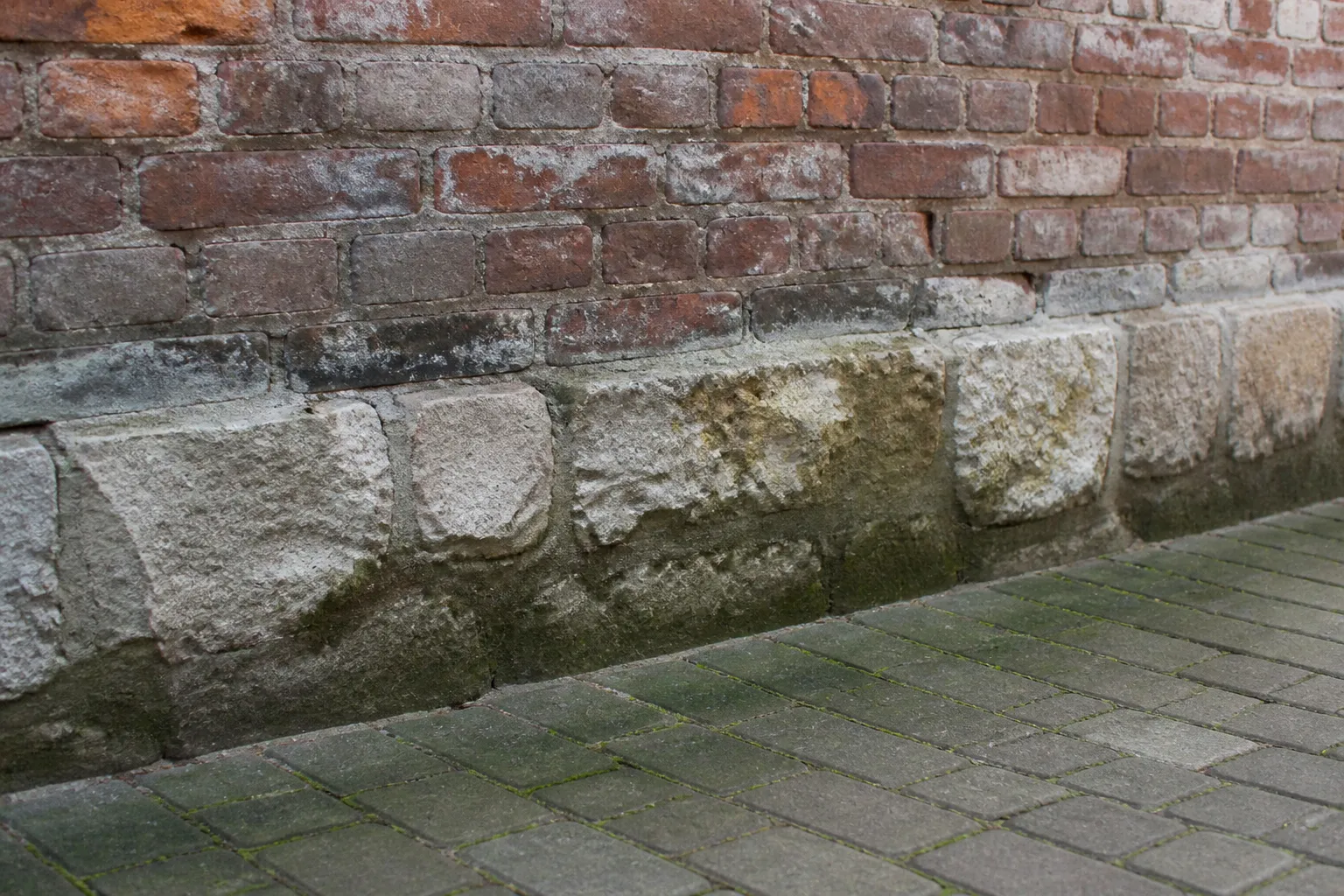 Pied de mur extérieur avec traces d’humidité et soubassement