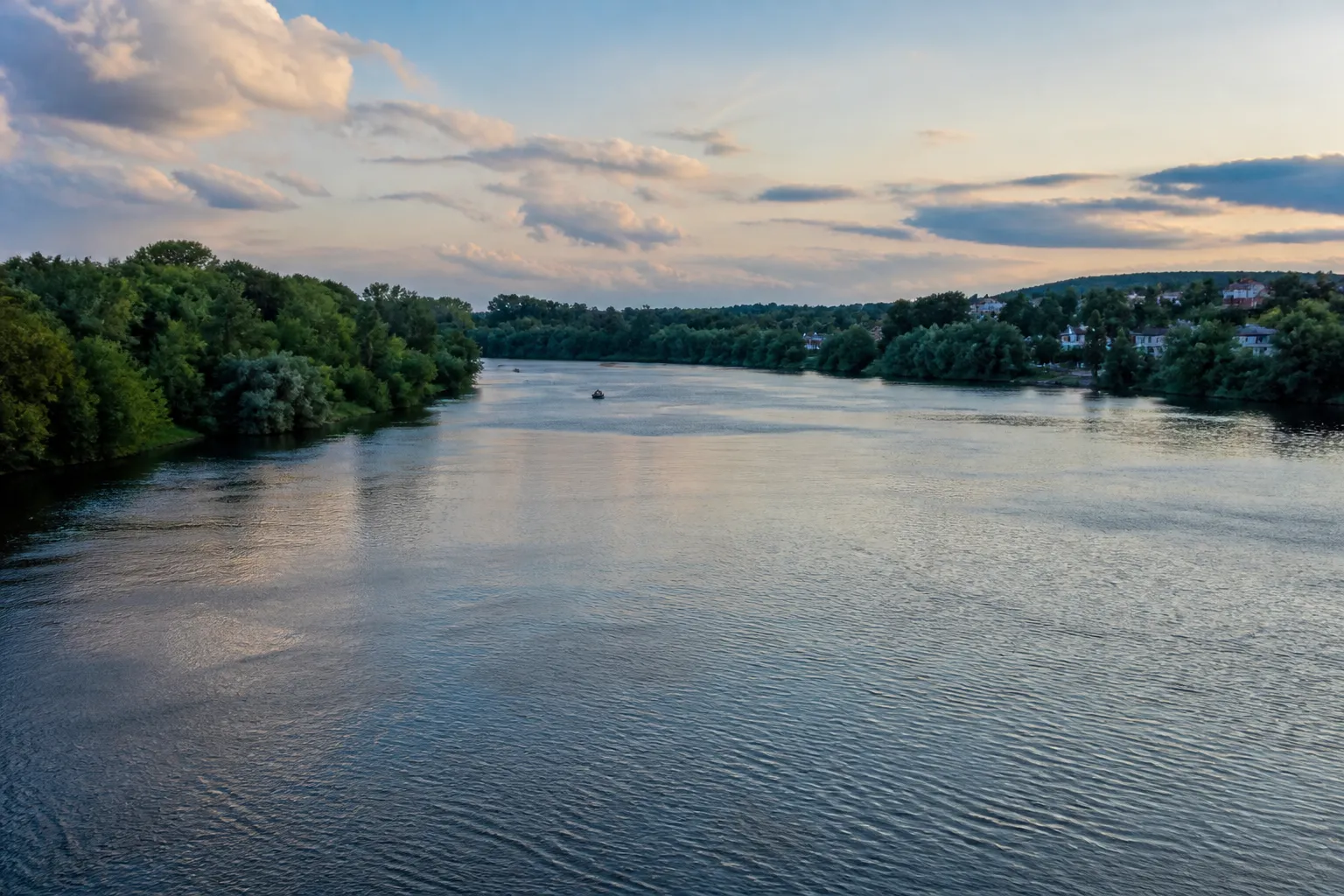 Rivière large aux berges boisées en périphérie de ville