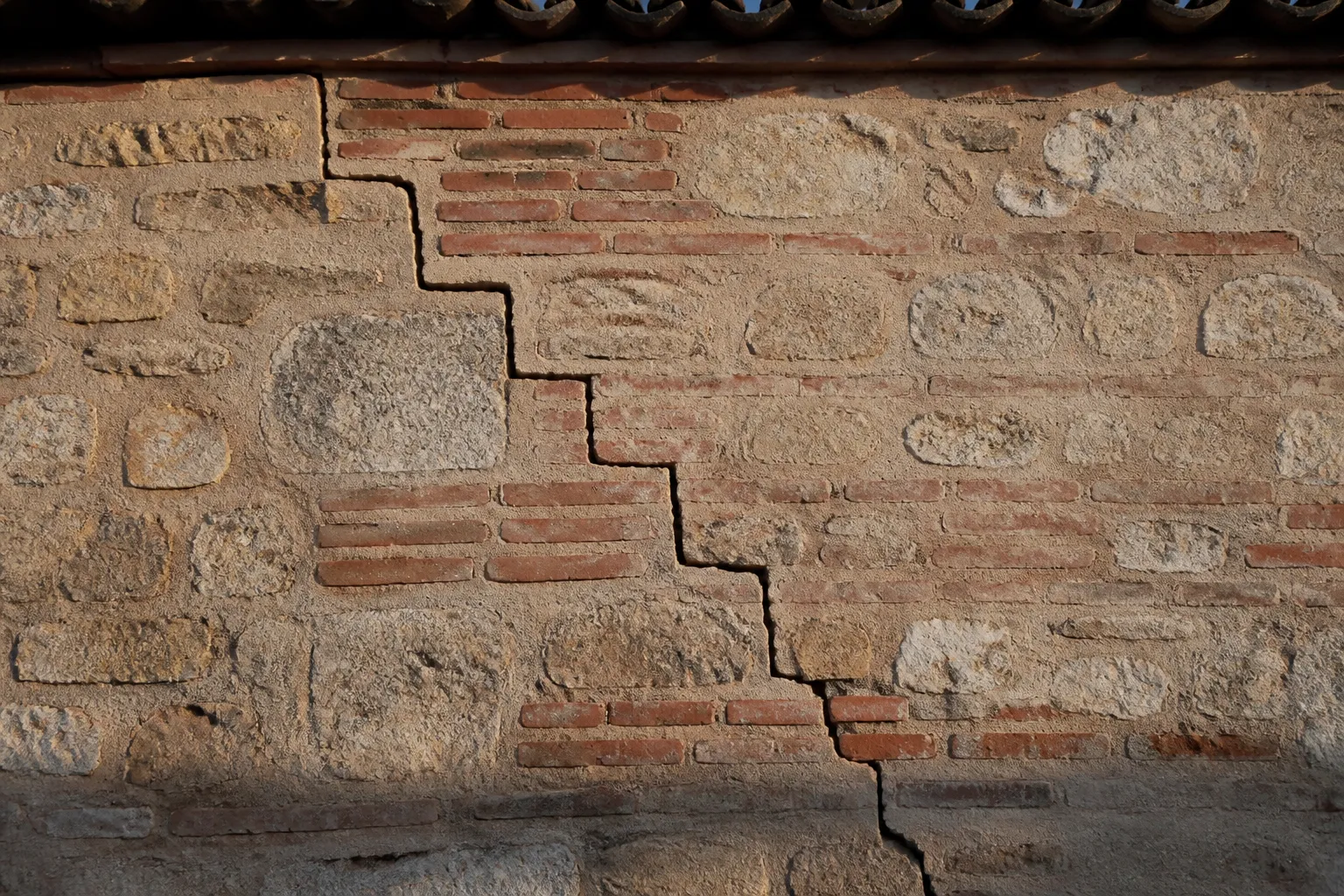 Fissure en escalier sur un mur de pierre jointoyé