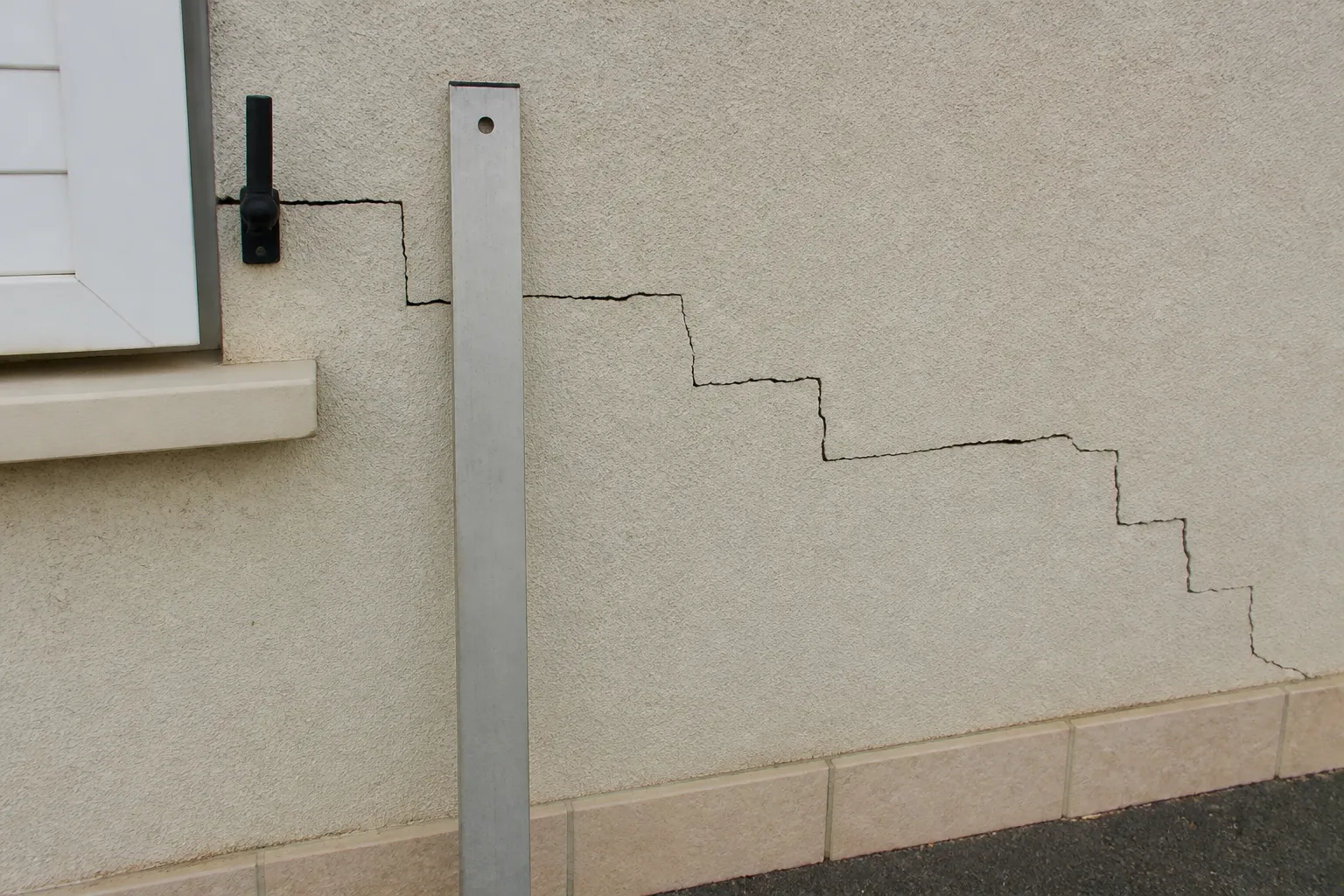 Fissure en escalier sur un mur extérieur en blocs enduits