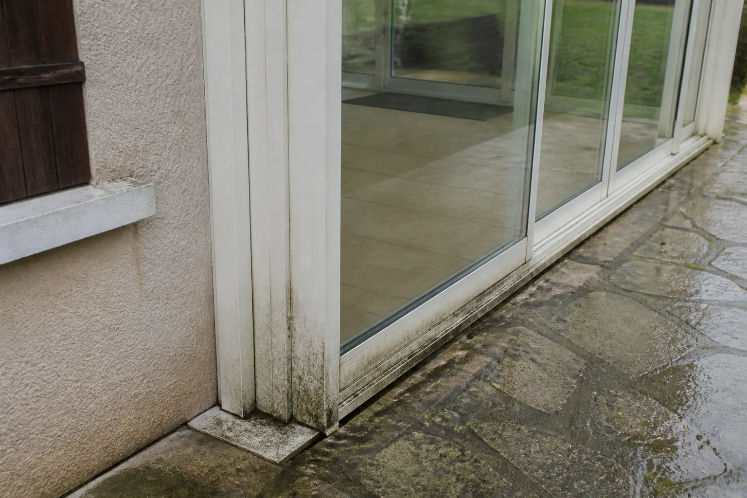 Véranda accolée à une maison avec traces d’humidité au sol