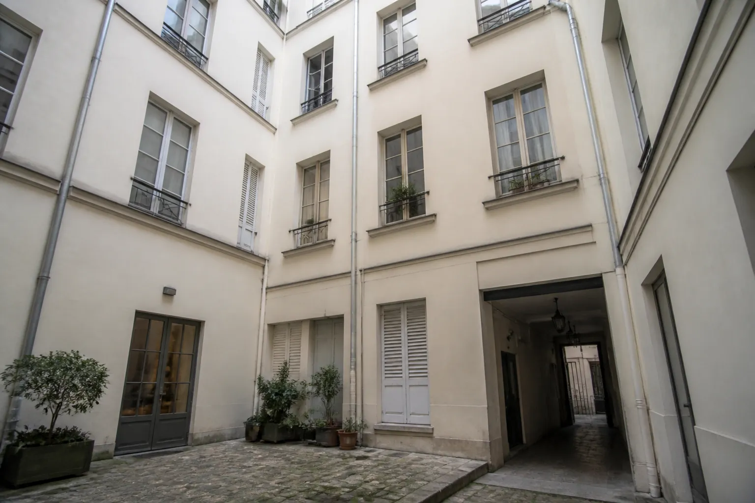 Cour intérieure d’une copropriété ancienne avec descentes d’eaux pluviales