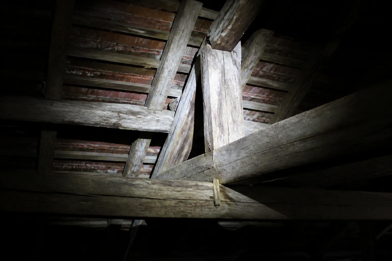 Charpente en bois dans des combles examinée à la lampe