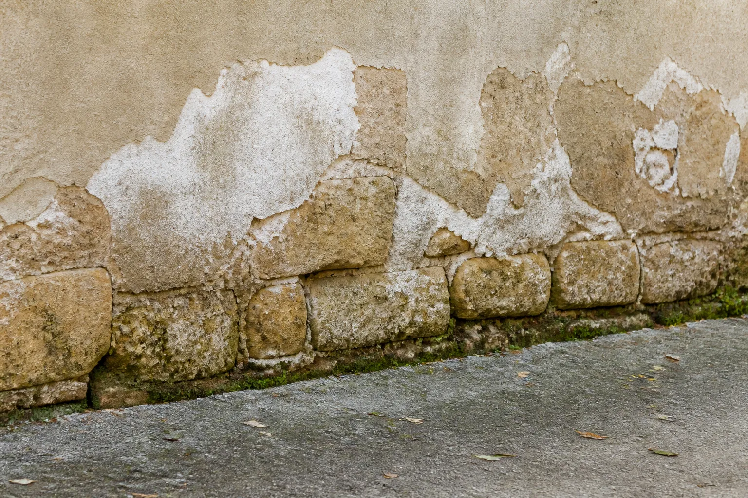 Pied de mur en pierre avec enduit dégradé par l’humidité