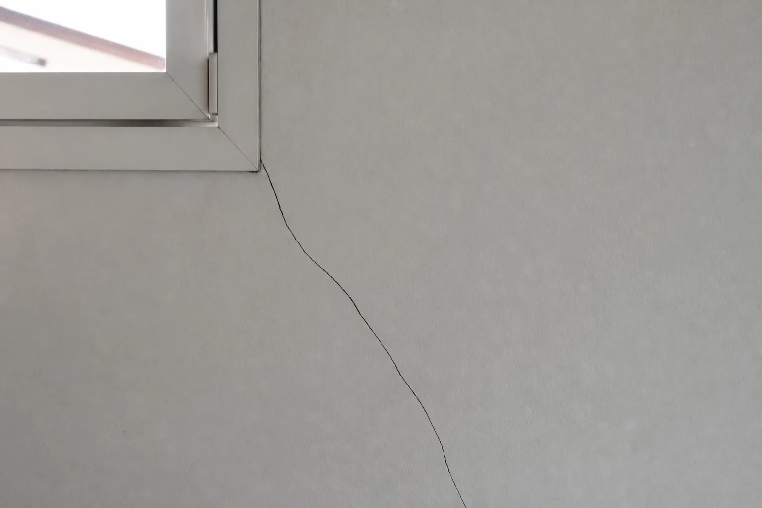 Fissure diagonale partant de l’angle d’une fenêtre sur un mur intérieur
