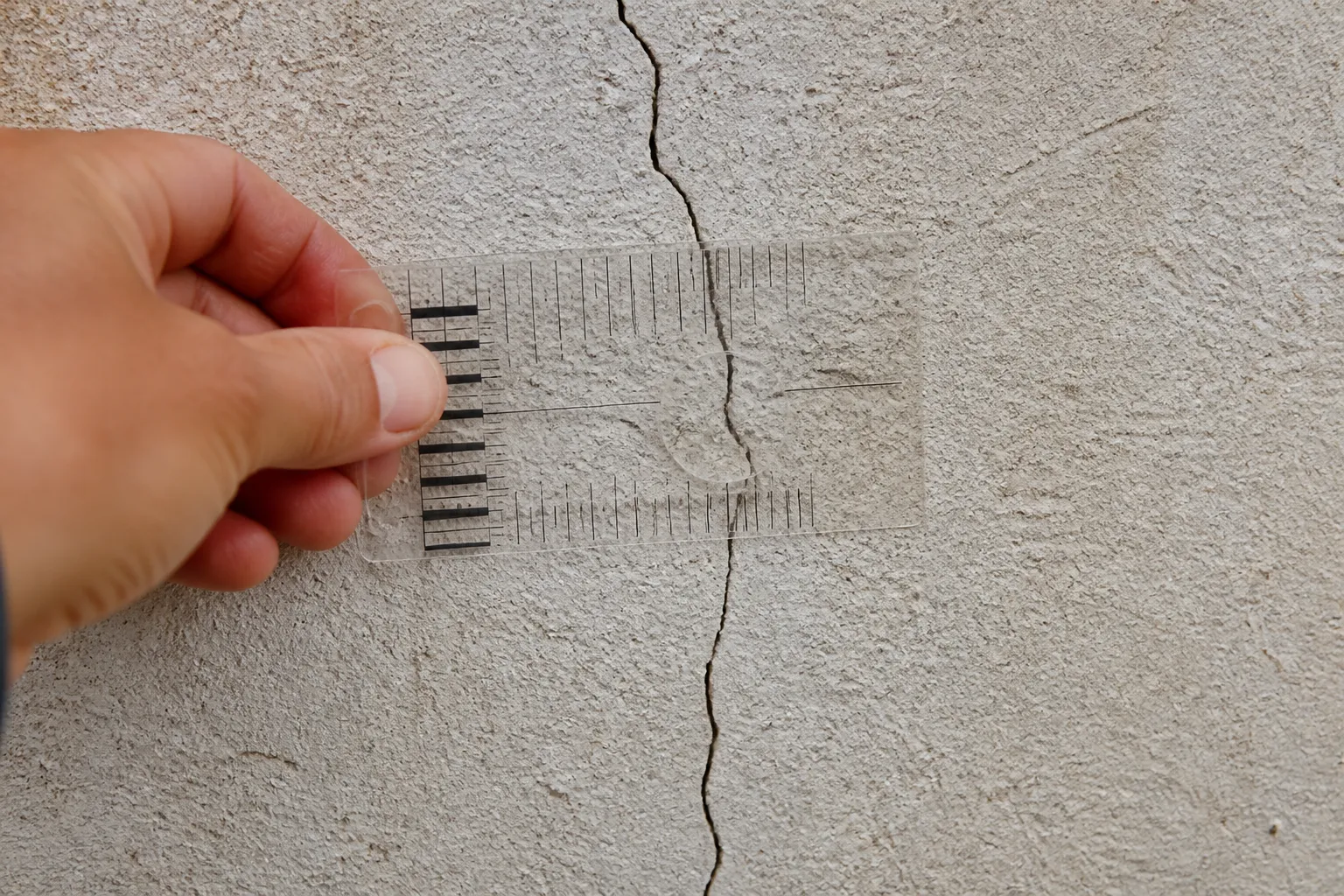 Expert mesurant l’ouverture d’une fissure avec un fissuromètre