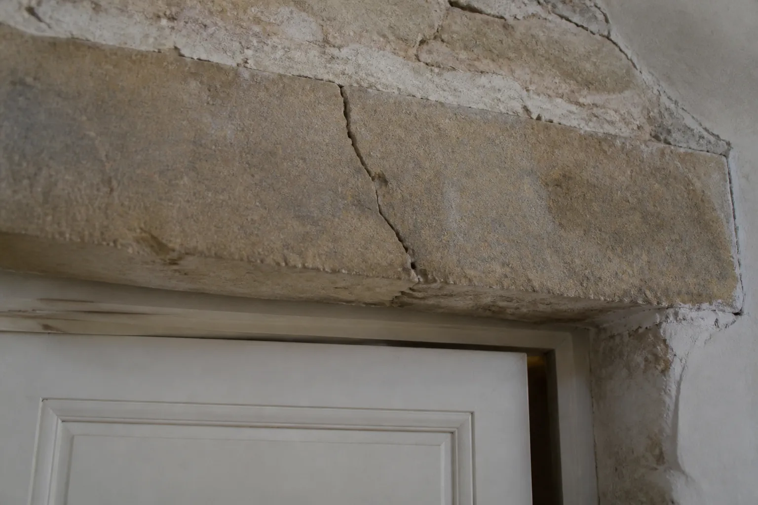 Linteau fissuré au-dessus d’une porte dans une maison en pierre