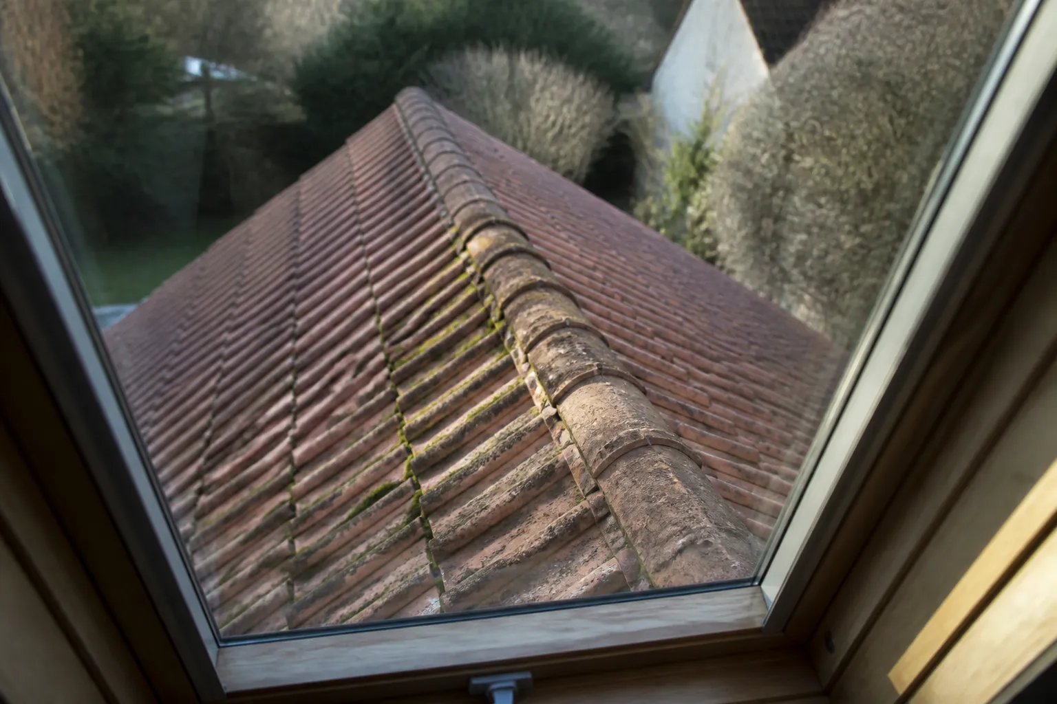 Tuiles et faîtage d’une toiture vus depuis une fenêtre de toit