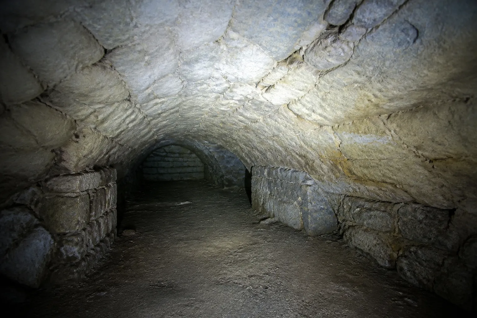 Cave voûtée en pierre éclairée par une lampe