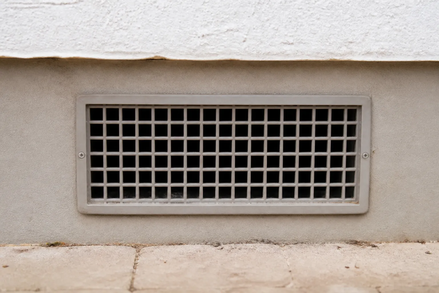 Grille de ventilation basse sur une façade de maison