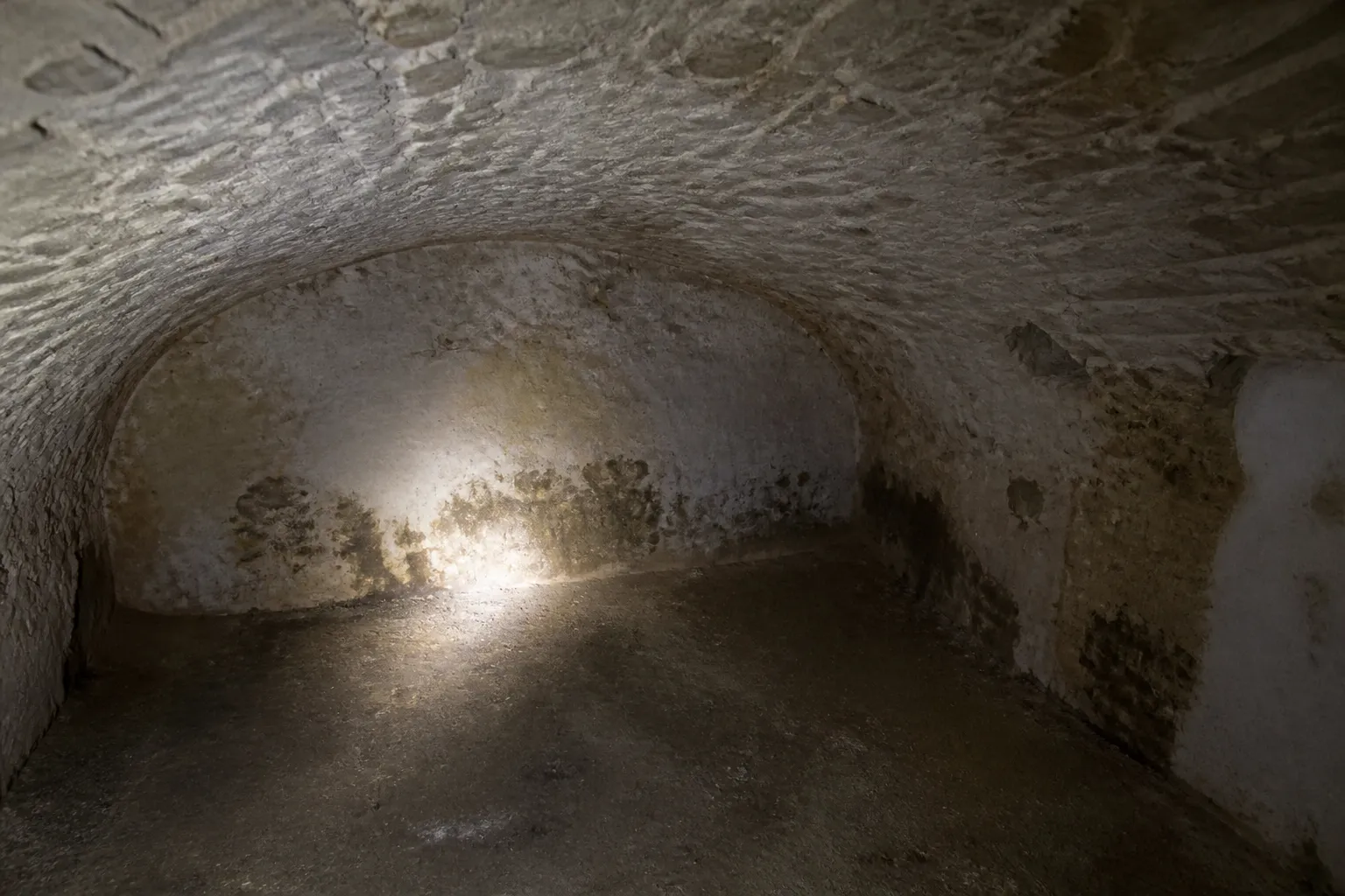 Cave voûtée en pierre d’une maison ancienne inspectée à la lampe