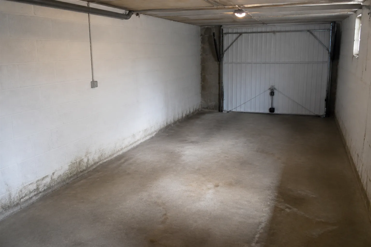 Garage en sous-sol avec traces d’humidité au pied des murs