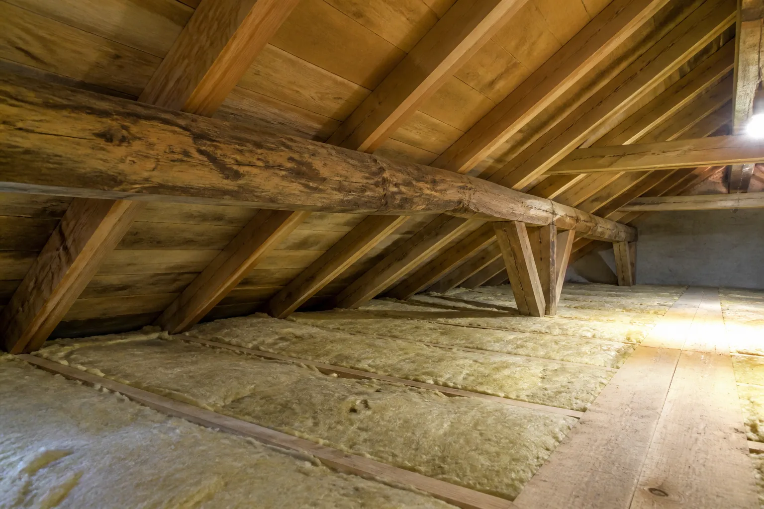 Combles avec charpente en bois et isolant observés à la lampe