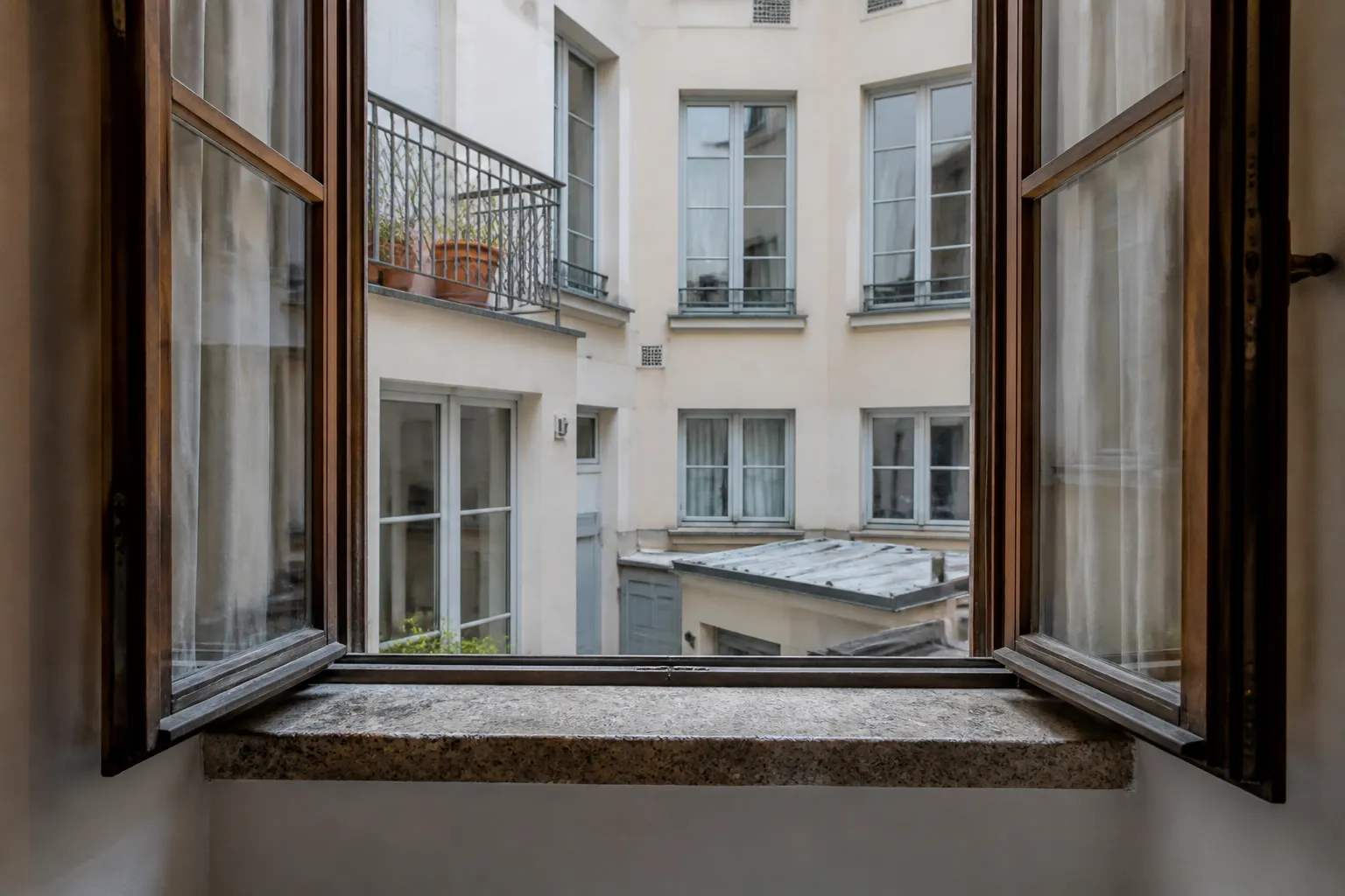 Fenêtre en bois ouverte sur une cour intérieure