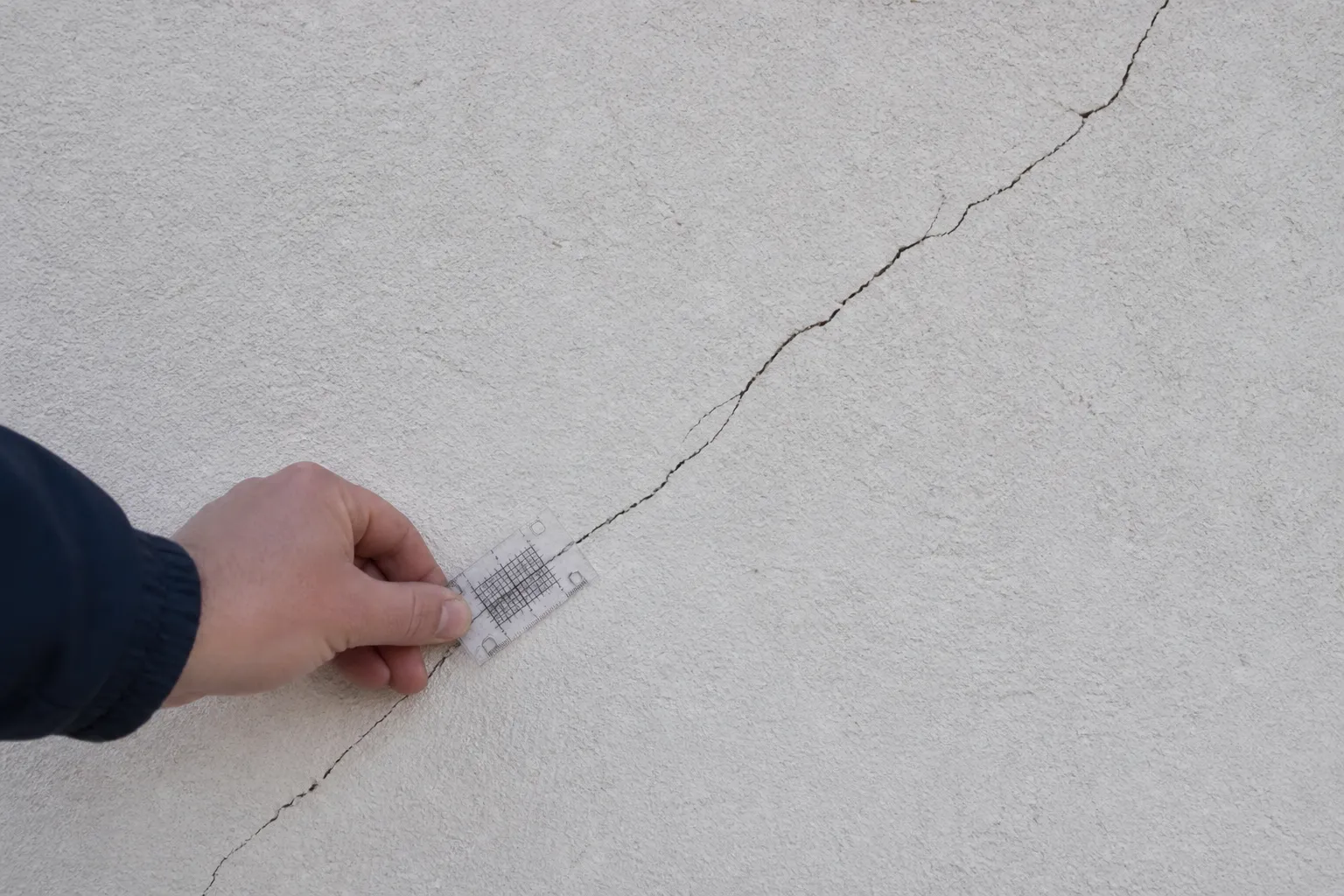 Fissure oblique sur un mur enduit observée par un expert