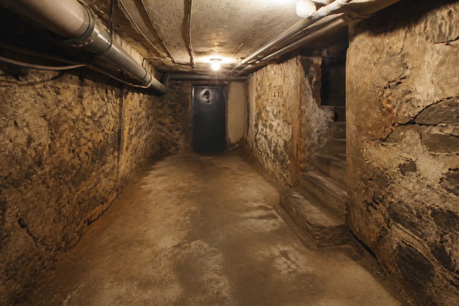 Cave d’immeuble avec murs humides et réseaux apparents