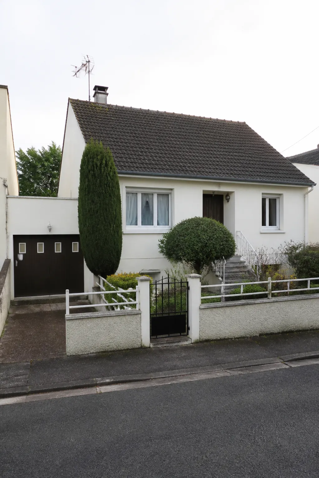 Pavillon avec garage en façade dans une rue résidentielle du Val-d’Oise