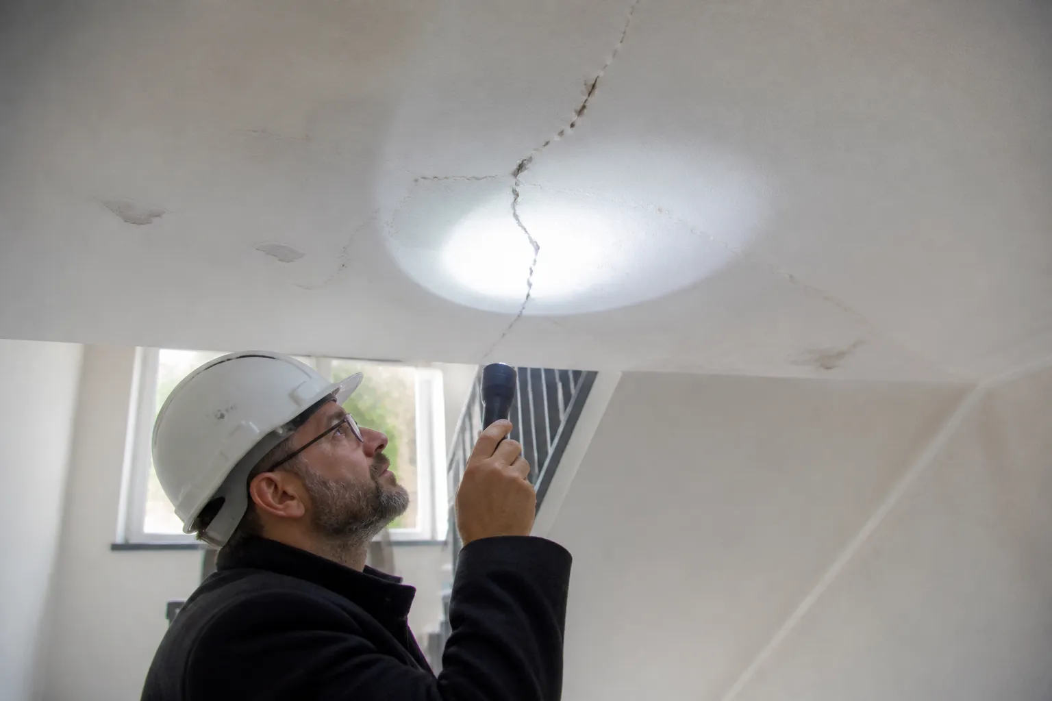Expert en bâtiment examinant un plafond de cage d’escalier