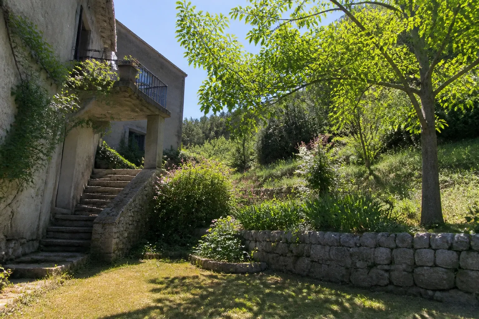 Jardin en pente et escalier extérieur en pierre derrière une maison