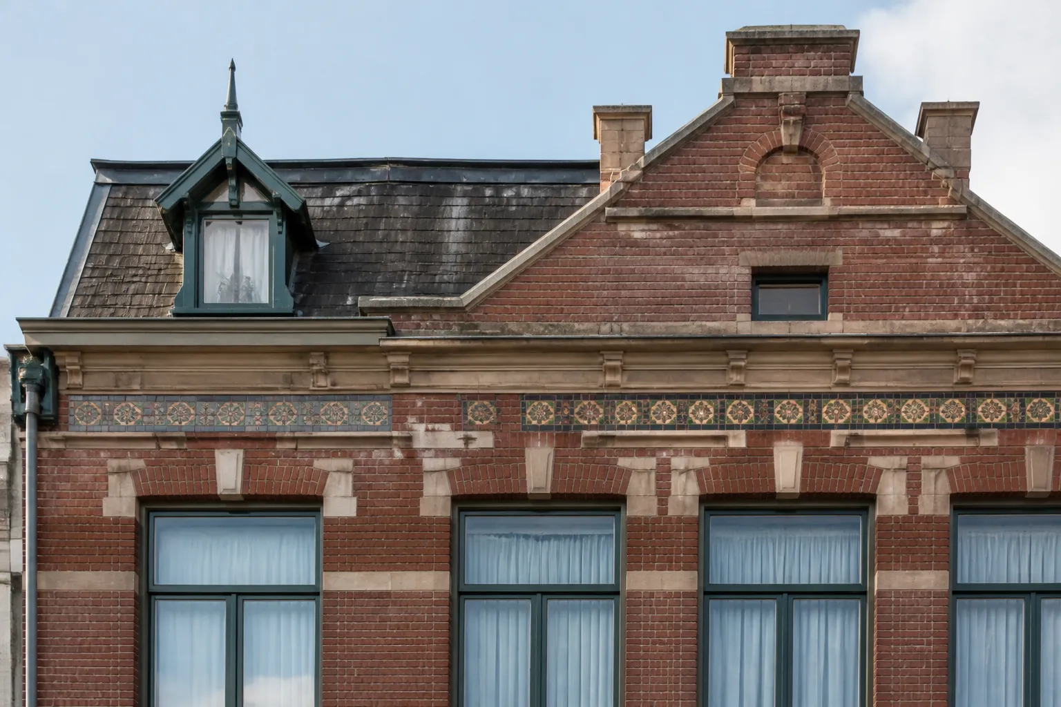 Façade de maison des années 1920 en brique avec décor de carreaux de faïence