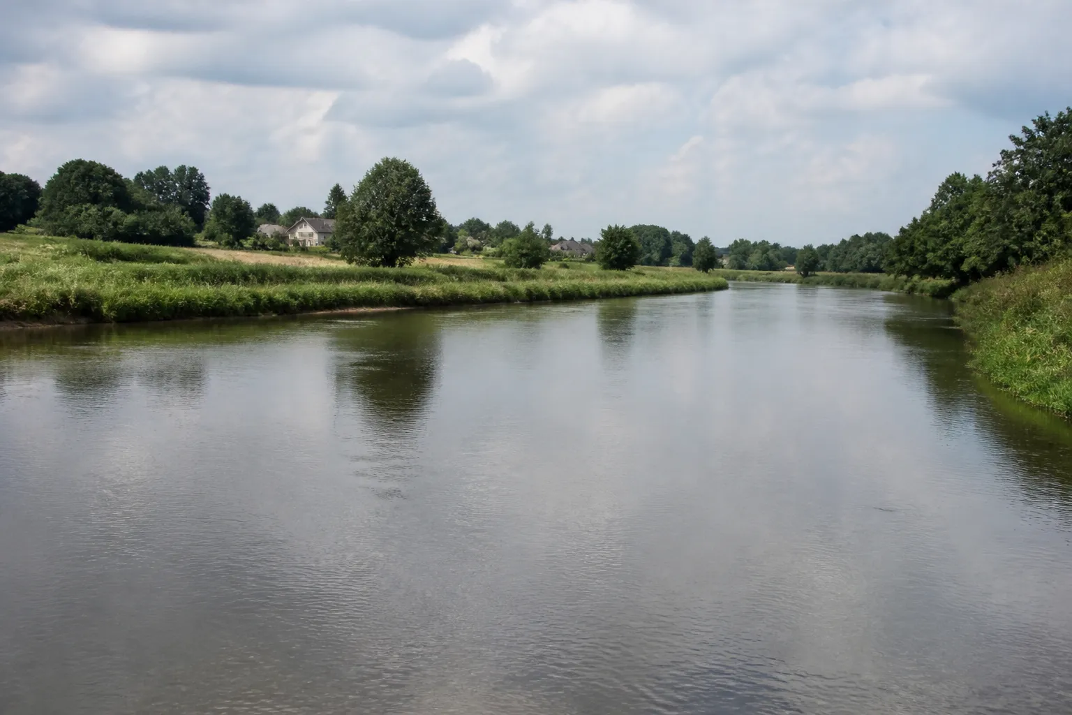 Rivière large bordée de prairies et de maisons