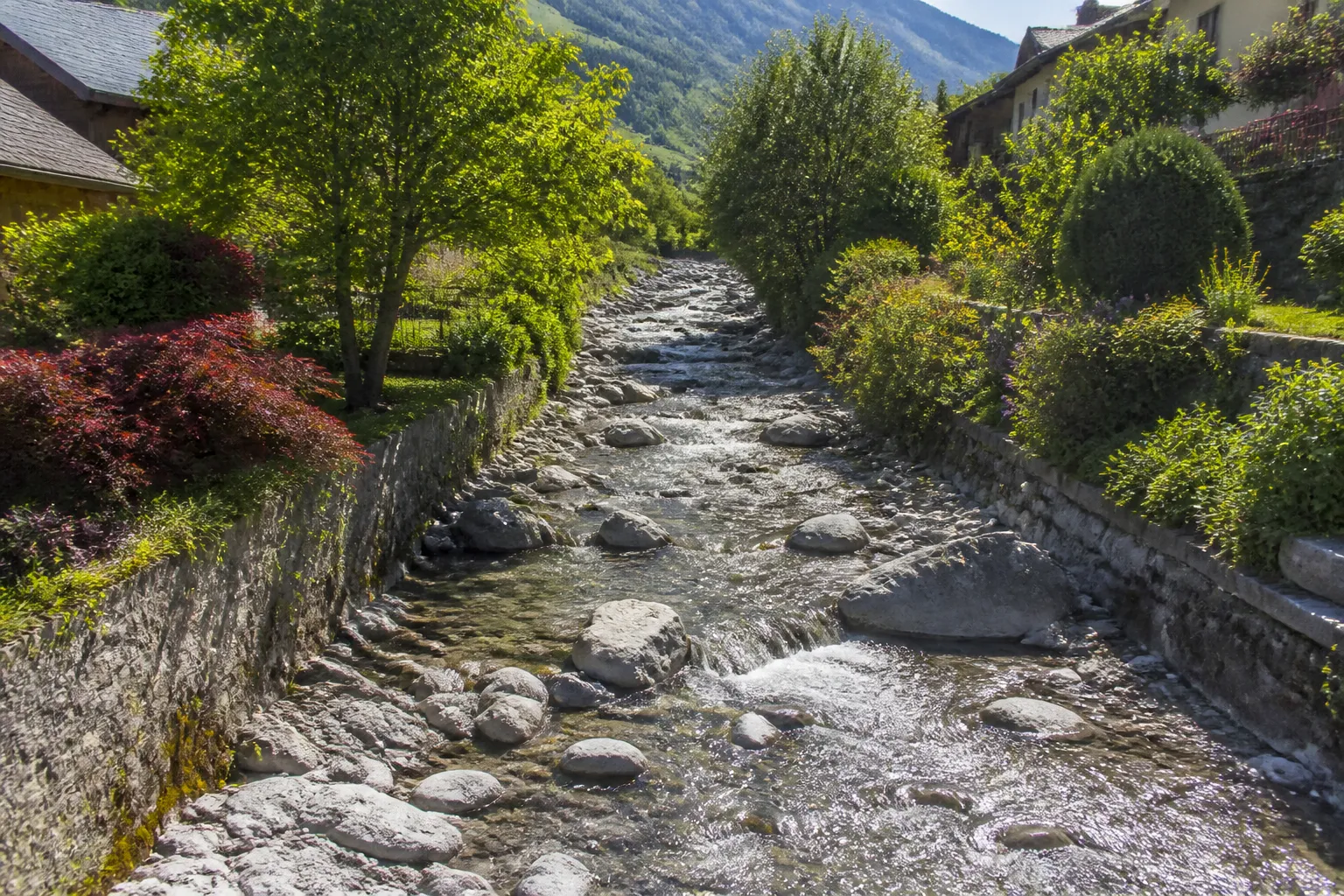 Torrent de montagne longeant des jardins en bordure de bourg