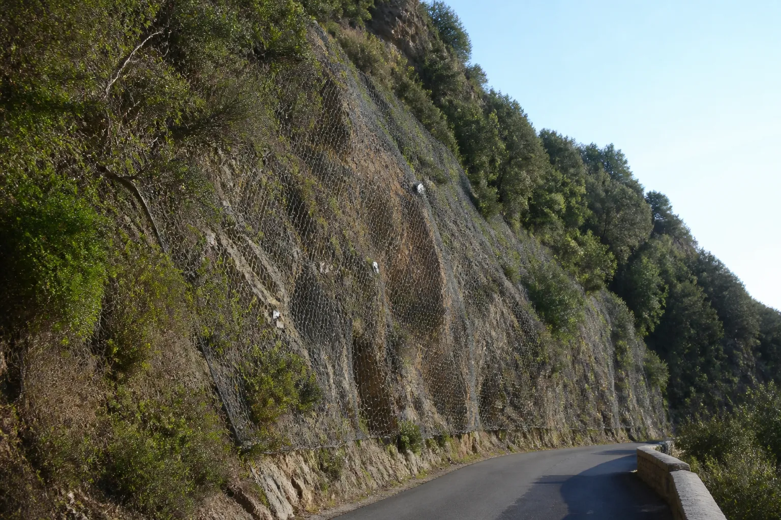 Talus rocheux et filet de protection au-dessus d’une route en pente