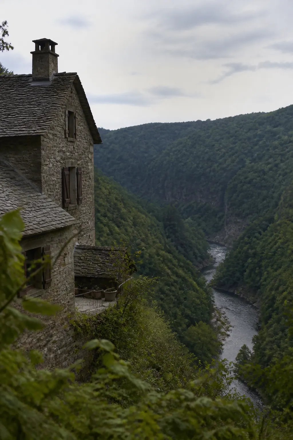 Maison en pierre sombre dans une vallée boisée des Ardennes