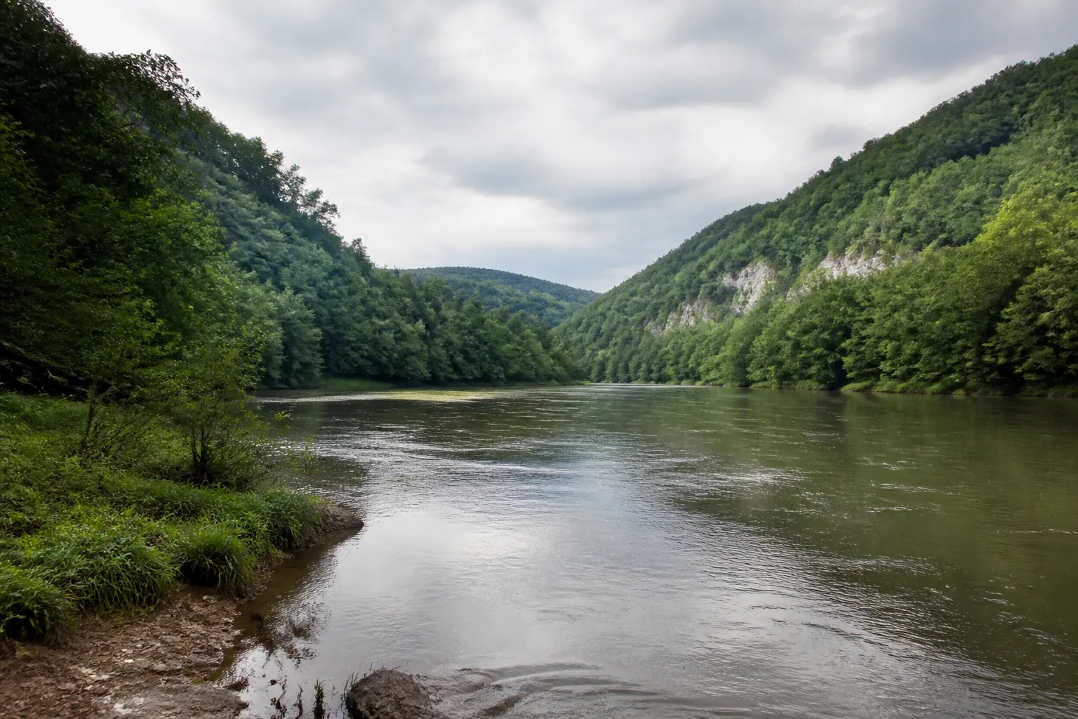 Rivière large et calme dans une vallée encaissée après une crue