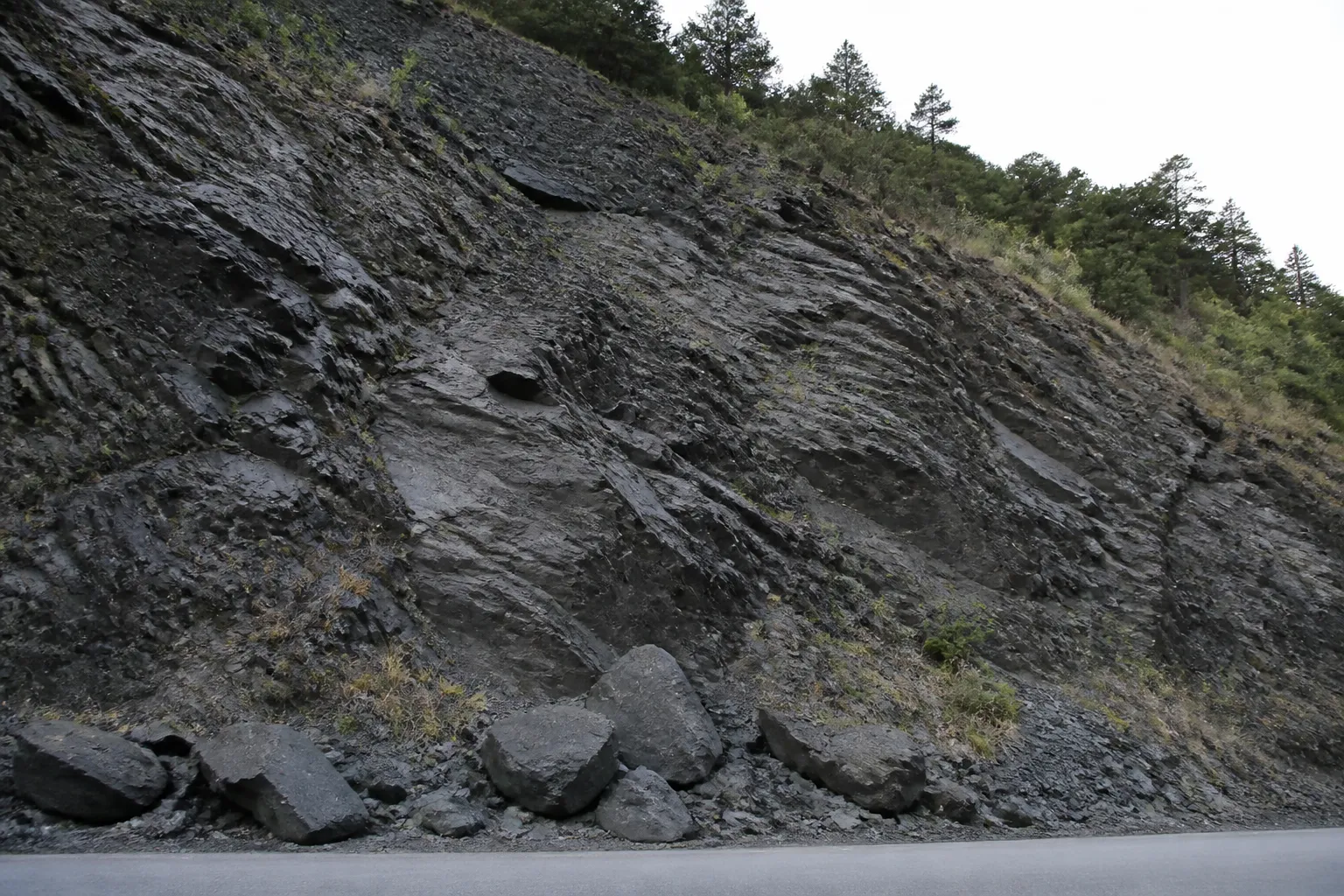 Versant rocheux de schiste au-dessus d’une route de vallée