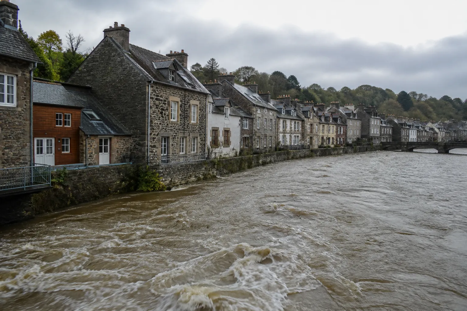 Rivière bordée de maisons en pierre après une période de pluie