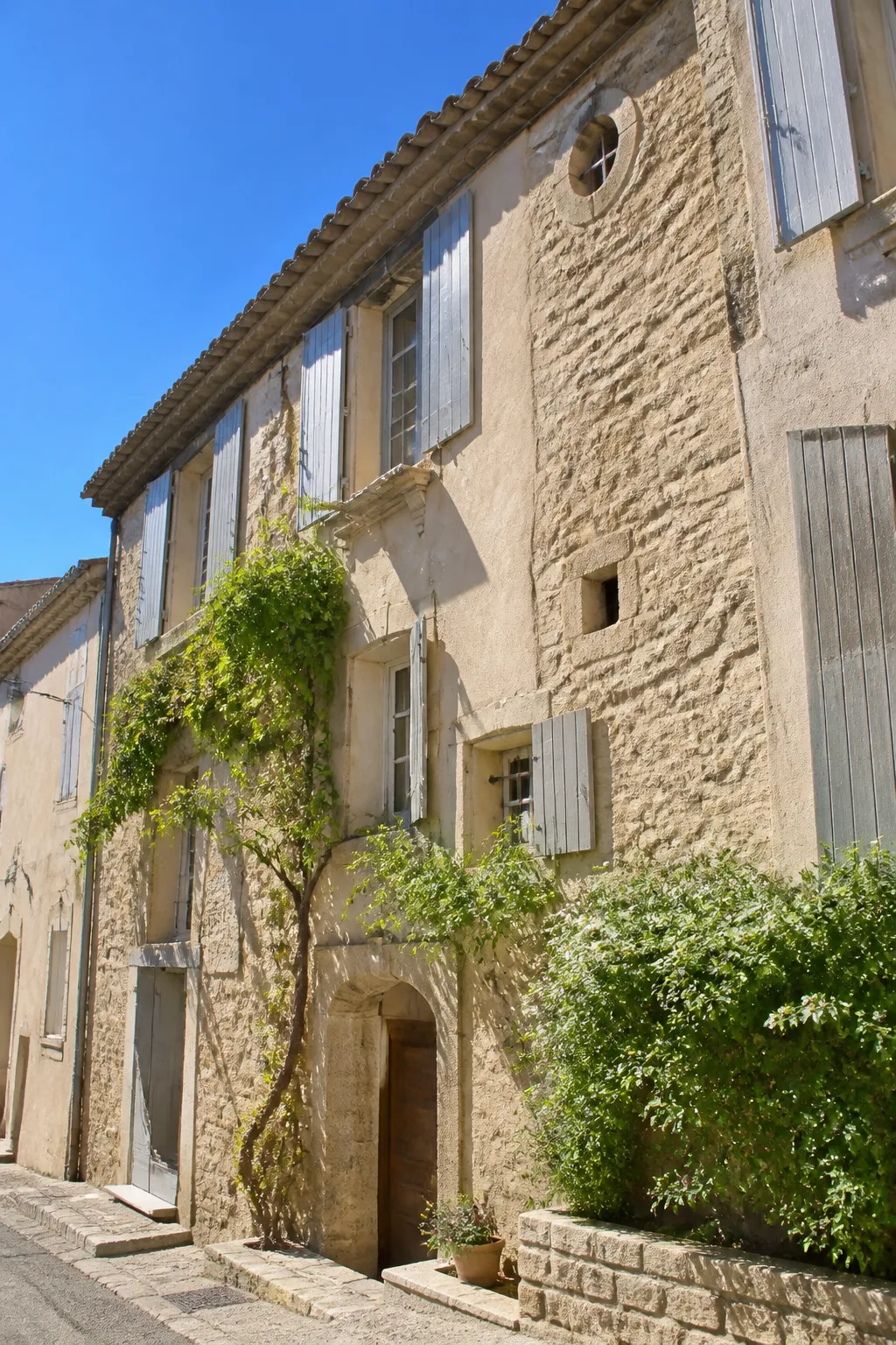 Façade d’immeuble ancien en pierre et enduit clair sous un ciel méditerranéen