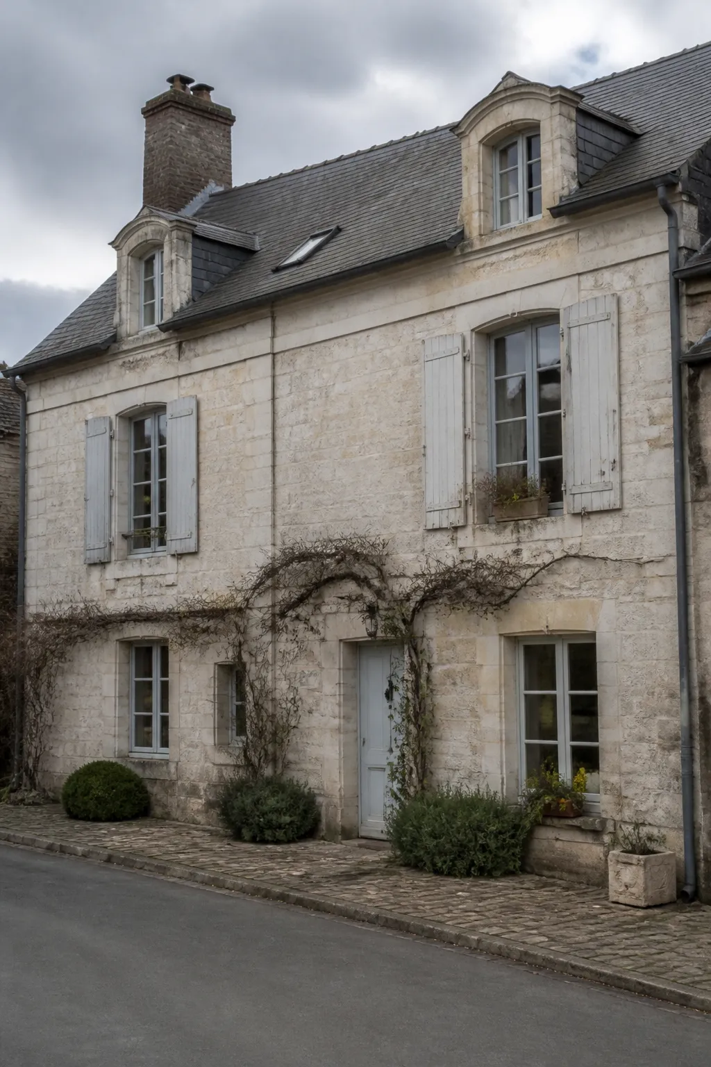 Façade de maison en pierre calcaire claire sous un ciel nuageux