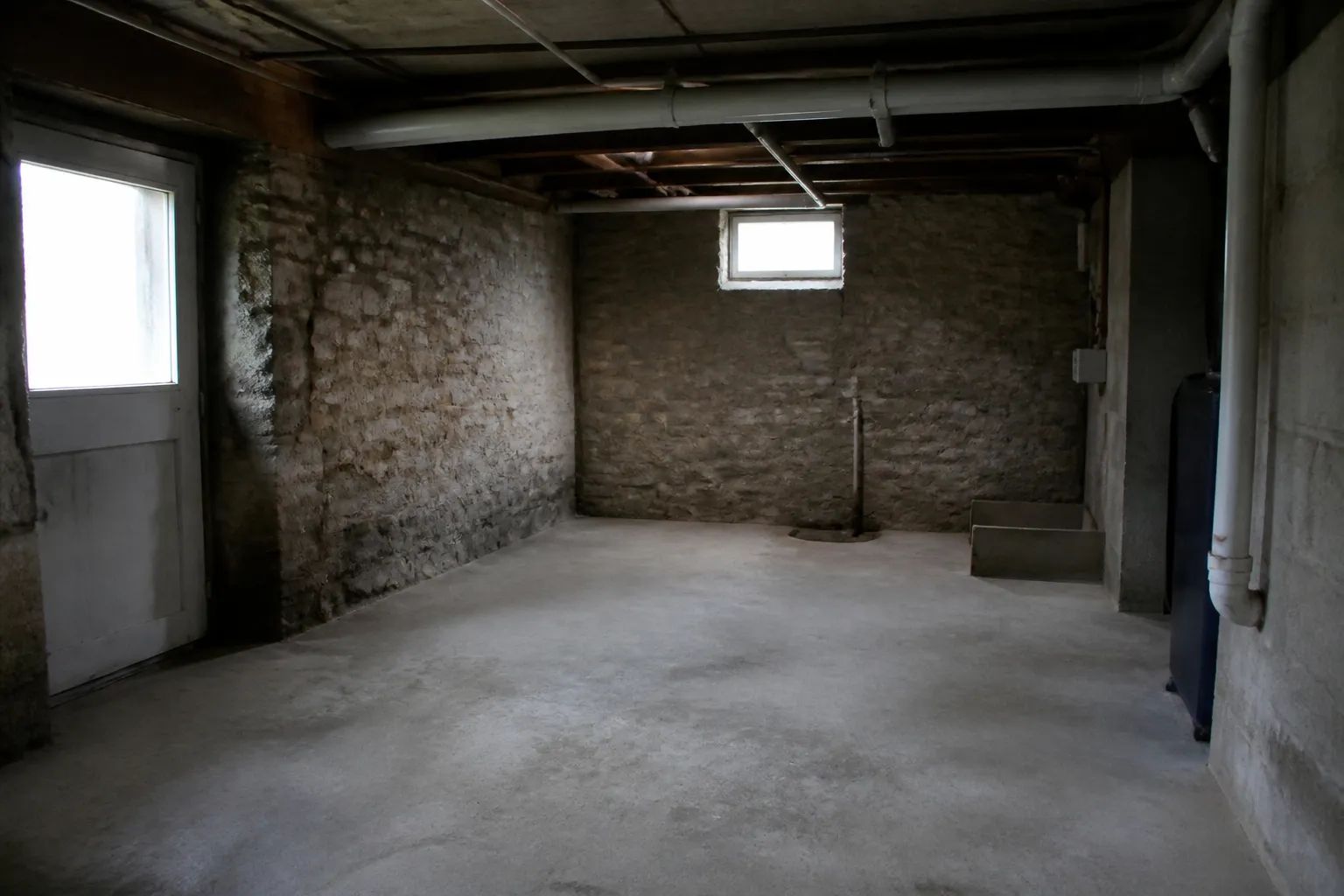 Sous-sol de maison avec mur en pierre et soupirail