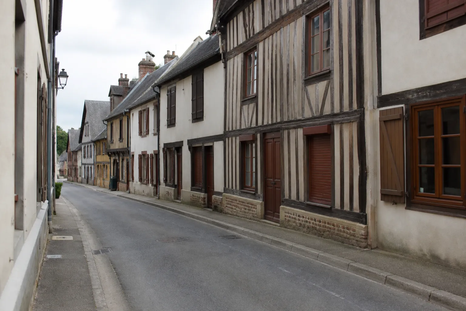 Rue de bourg avec maisons mitoyennes à pans de bois et façades enduites