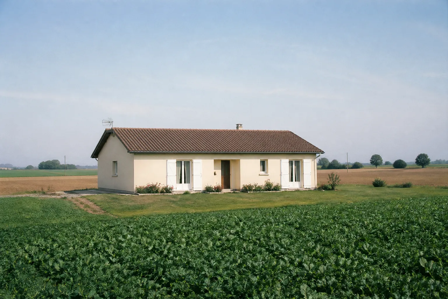 Pavillon des années 1980 sur un plateau agricole, vu depuis la rue