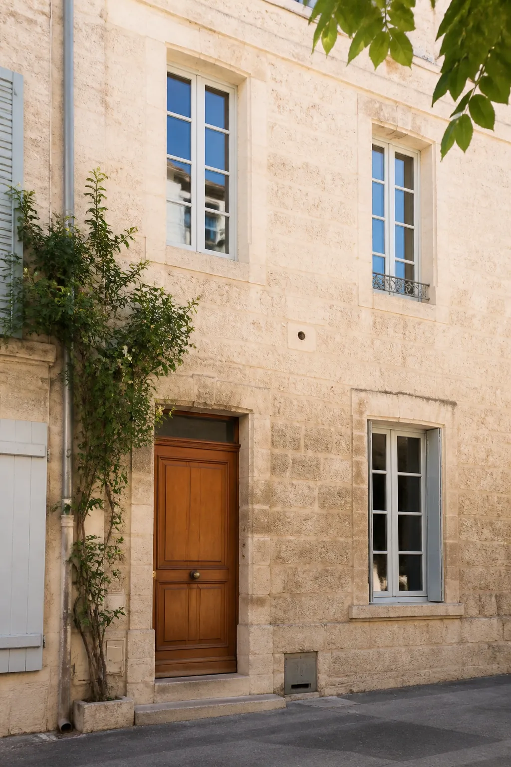 Façade en pierre claire d’une maison de ville avec porte en bois
