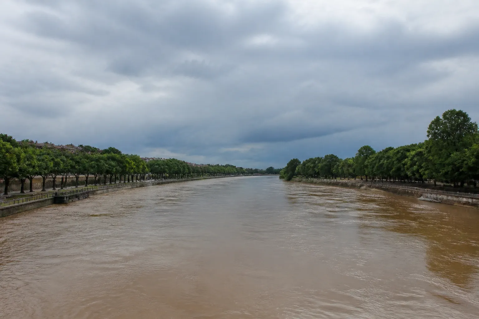 Fleuve large aux eaux brunes bordé de quais