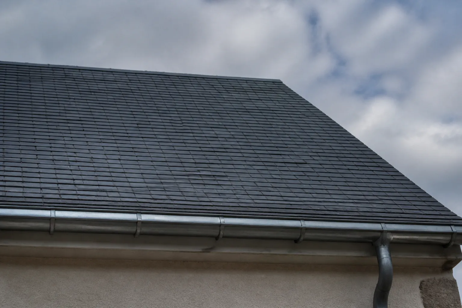 Toiture en ardoise vue depuis le sol avec une gouttière en zinc