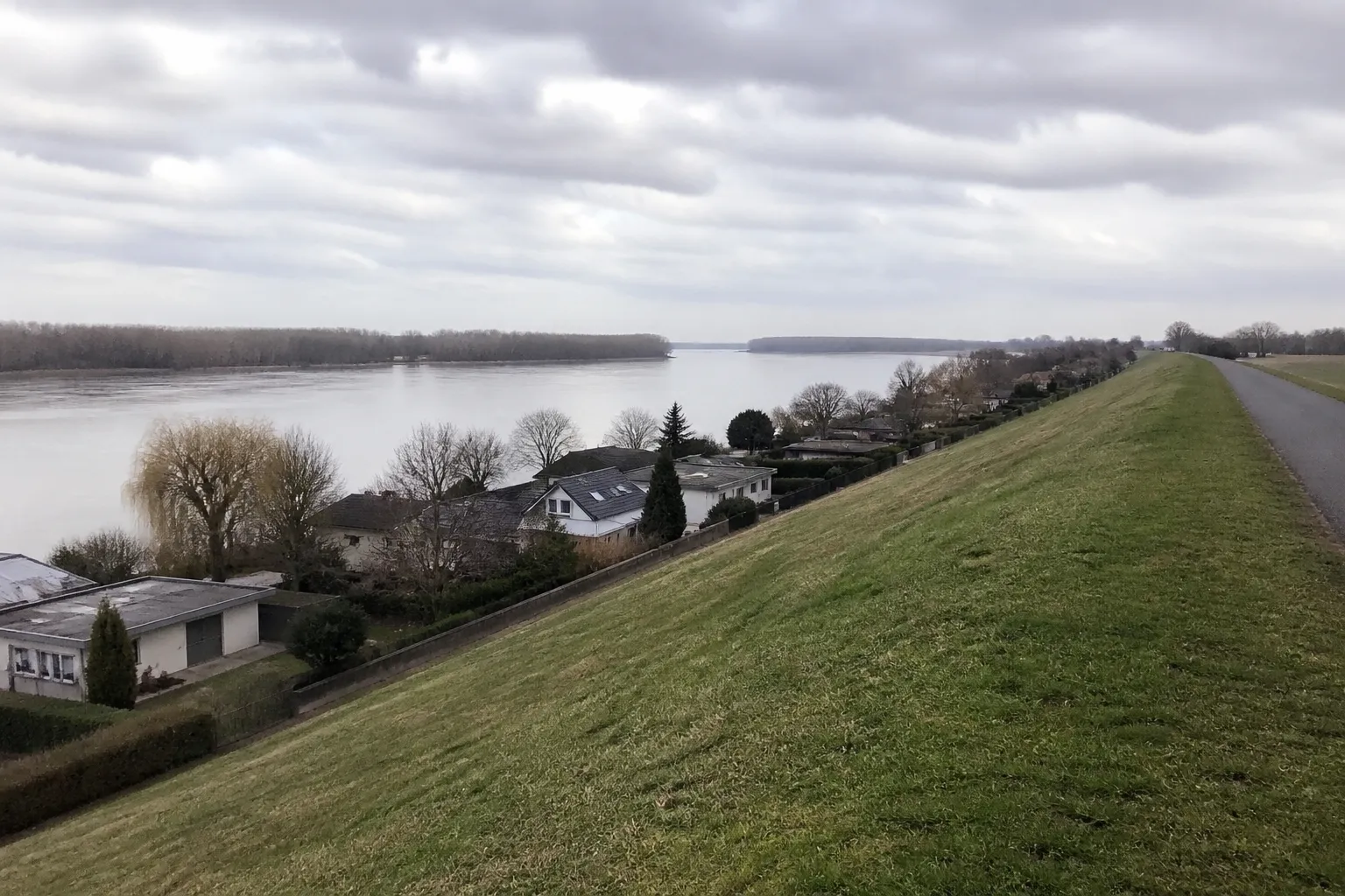 Levée enherbée le long d’un fleuve avec des maisons en contrebas